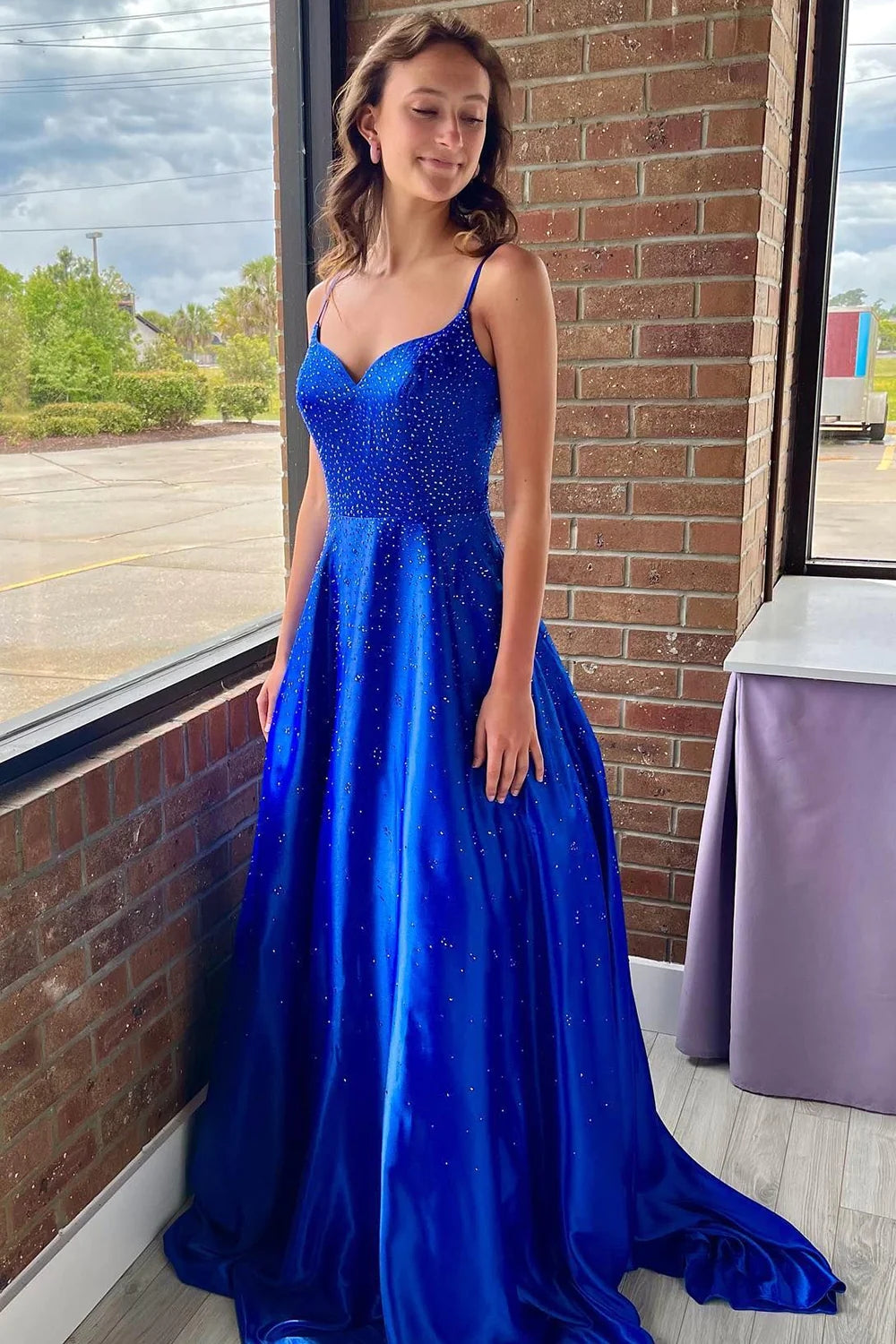 Vestido largo de fiesta azul real con tirantes finos, corte en A y detalles de pedrería.