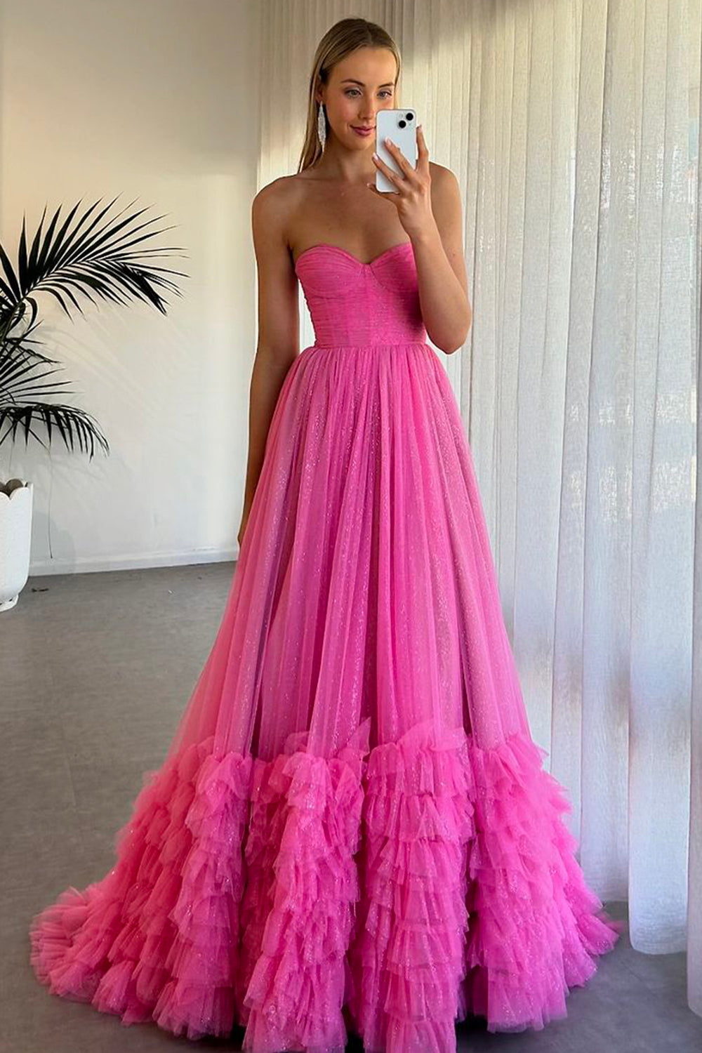 Robe de bal longue en tulle à décolleté cœur, coupe trapèze, corset à volants et fente.