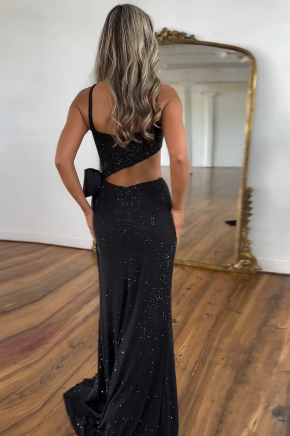 Robe de bal longue sirène à fines bretelles noires pailletées et découpes ornée de perles