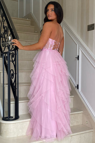 Robe de bal longue bustier en tulle rose poudré, coupe trapèze, à volants et corset orné d'appliques