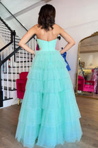 Robe de bal longue trapèze en tulle à volants et décolleté cœur, avec fente.