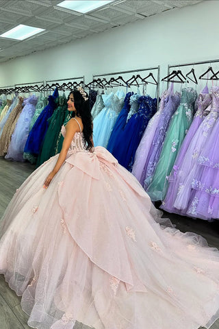 Robe de princesse rose à fines bretelles en tulle ornée d'appliqués et d'un nœud, idéale pour une quinceañera.
