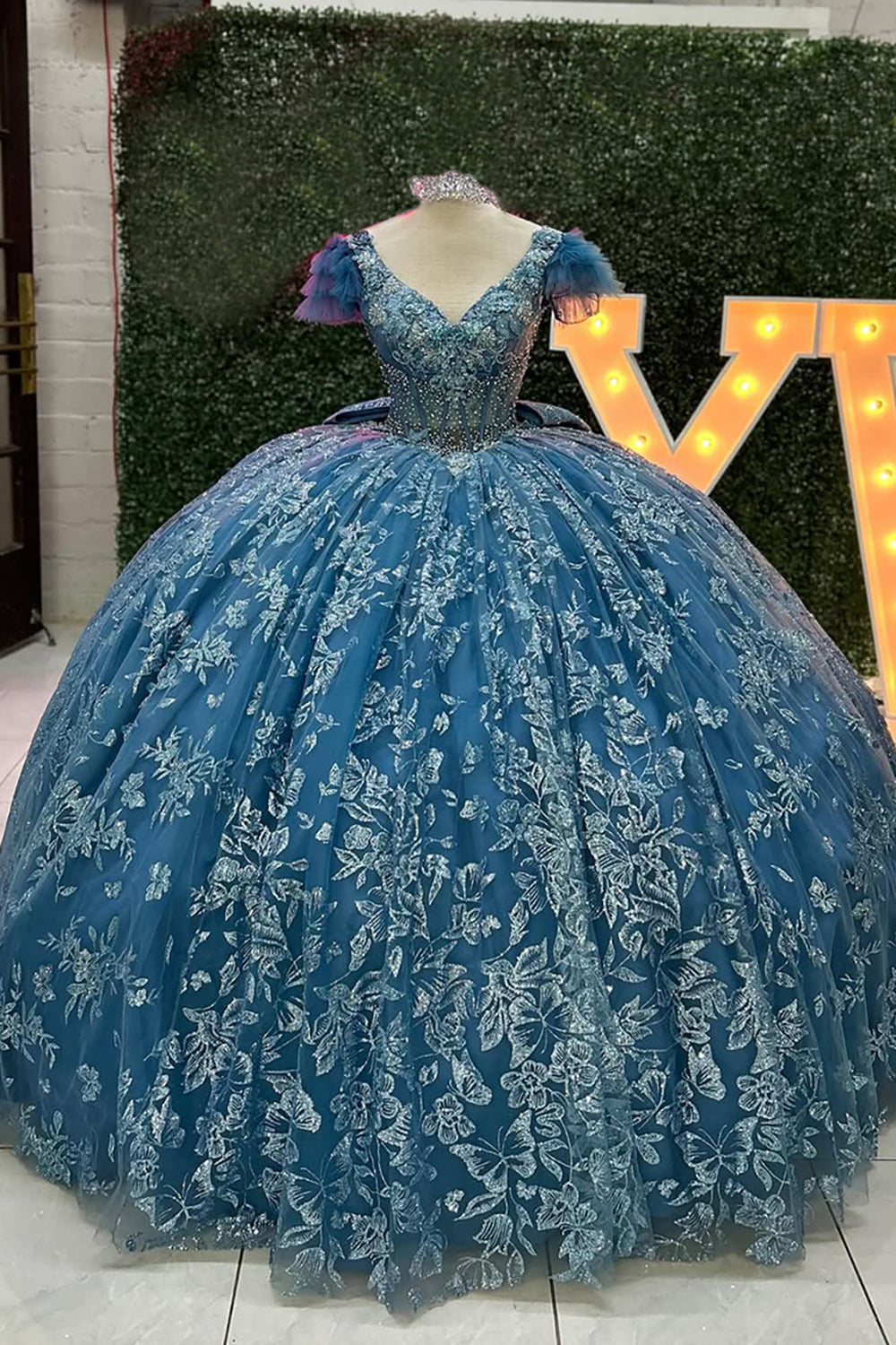 Robe de princesse grise et bleue à col en V, manches courtes et traîne, avec col en V et ornée d'appliqués.