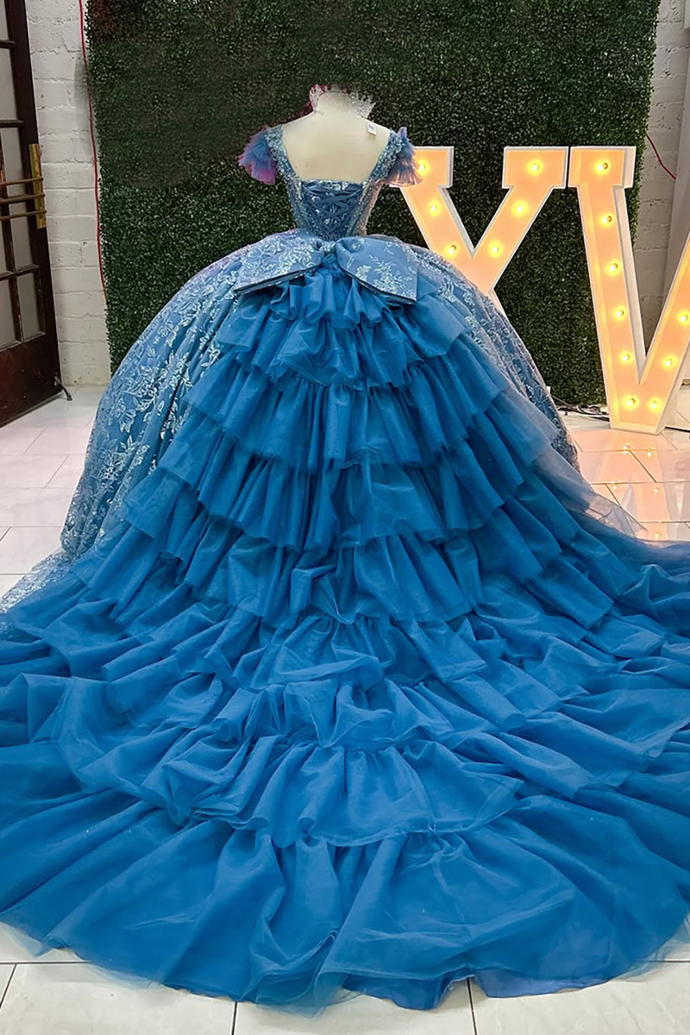 Robe de princesse grise et bleue à col en V, manches courtes et traîne, avec col en V et ornée d'appliqués.