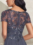 Vestido largo de corte A, color gris carbón, con escote redondo y detalles de pedrería, ideal para la madre de la novia.