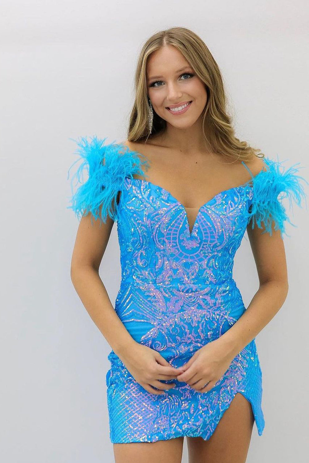 Vestido corto morado de fiesta, estilo tubo, con hombros descubiertos y detalles de plumas.