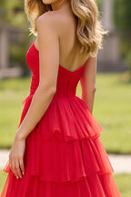Robe de bal longue rouge à col carré, coupe trapèze et volants, fendue.