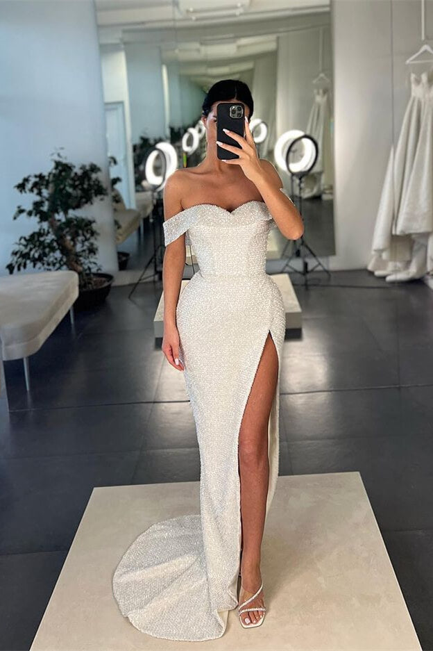 Vestido de fiesta blanco de sirena con lentejuelas, hombros descubiertos y abertura.