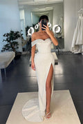 Vestido de fiesta blanco de sirena con lentejuelas, hombros descubiertos y abertura.