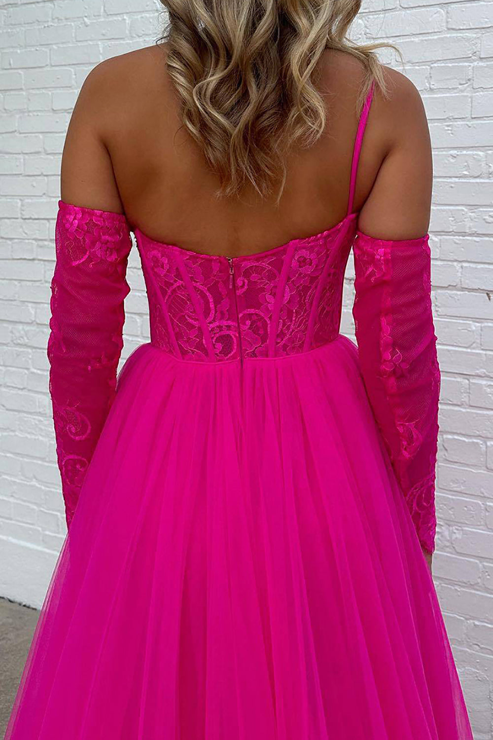 Vestido de fiesta fucsia de corte A, corte asimétrico, con corsé y abertura frontal.
