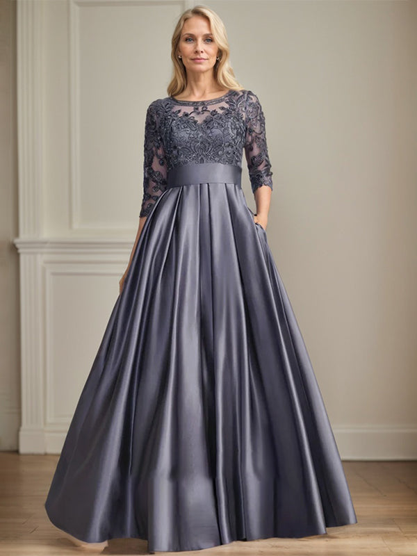 Robe de mariée longue en satin et dentelle, coupe trapèze, décolleté illusion, ornée d'un nœud à sequins. 