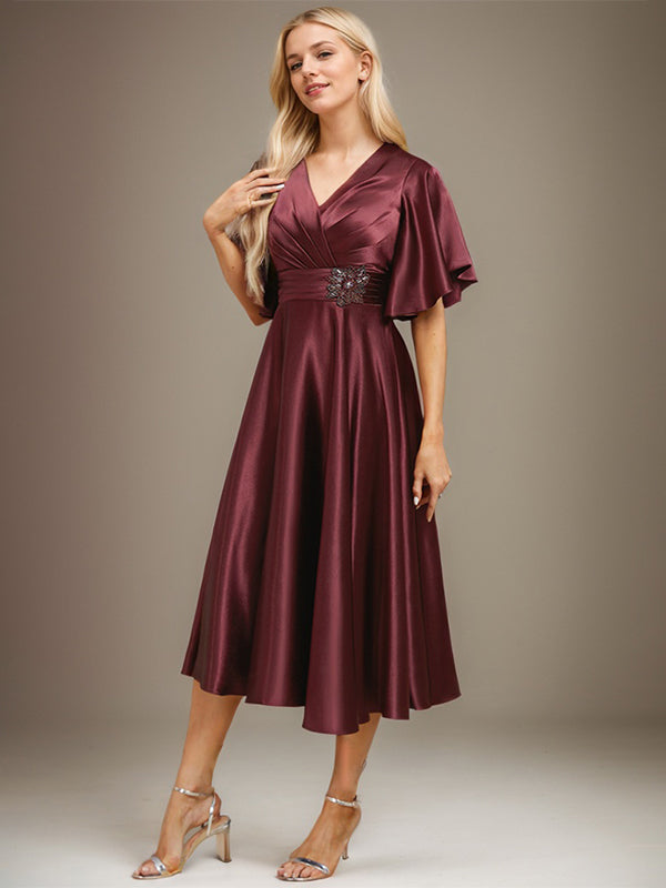 Vestido de novia de satén elástico, corte en A, escote en V, largo hasta la rodilla, con cuentas y pliegues. 