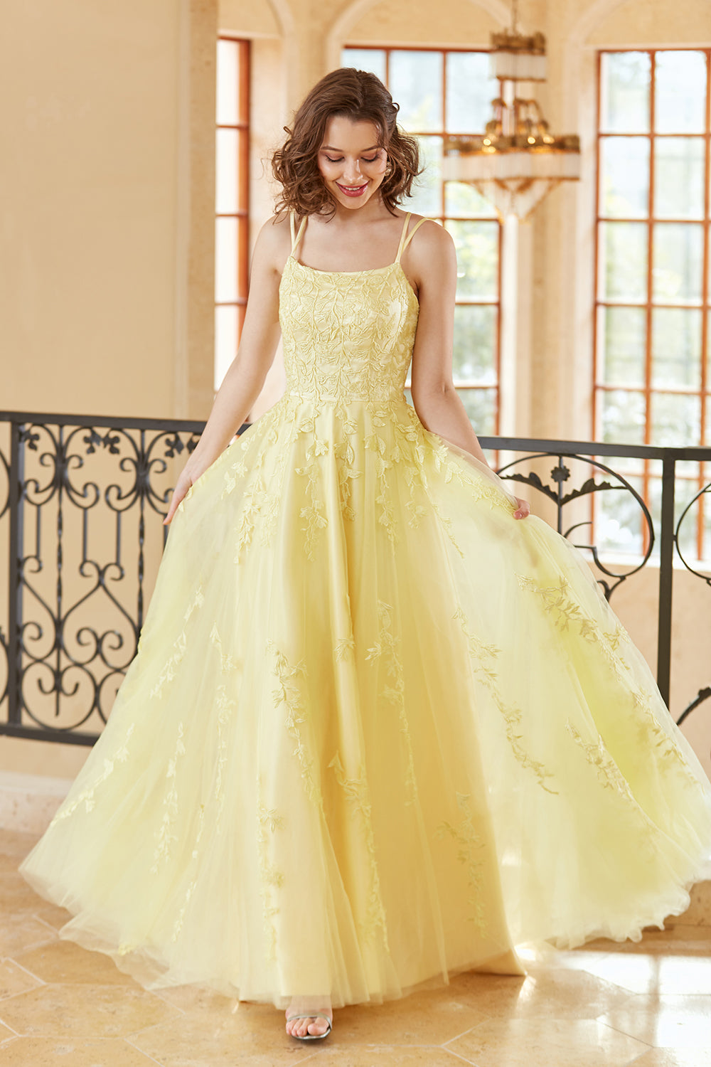 Magnifique robe de bal longue jaune à bretelles spaghetti et coupe trapèze, ornée d'appliqués.