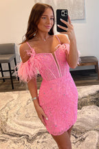 Vestido corto rosa fucsia de corte sirena con hombros descubiertos y detalles de plumas.