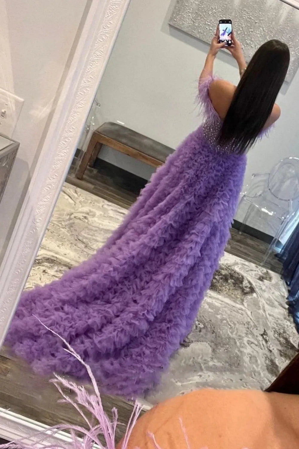 Robe de bal longue bustier trapèze en tulle à épaules dénudées et à volants, ornée de plumes.