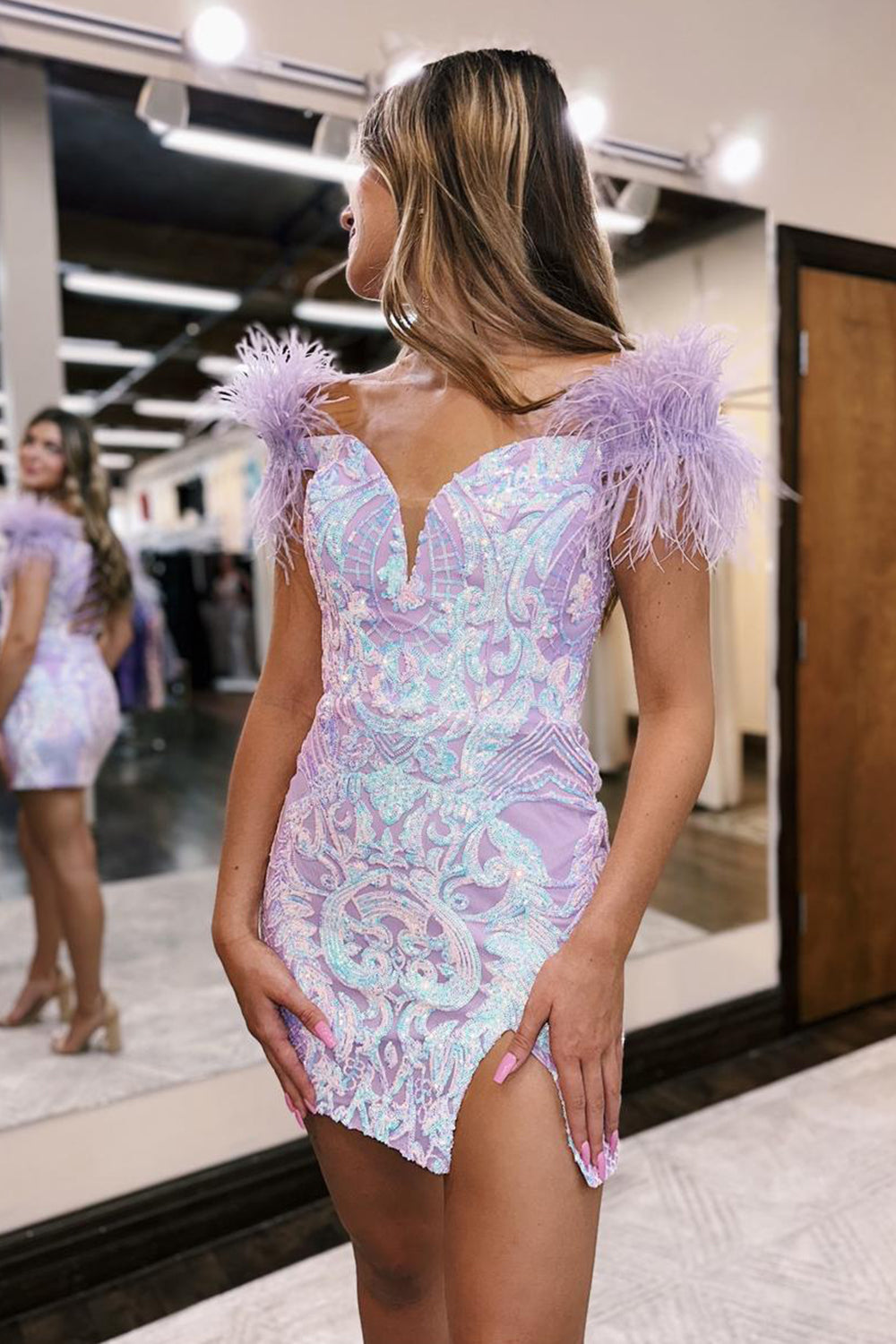 Vestido corto morado de fiesta, estilo tubo, con hombros descubiertos y detalles de plumas.