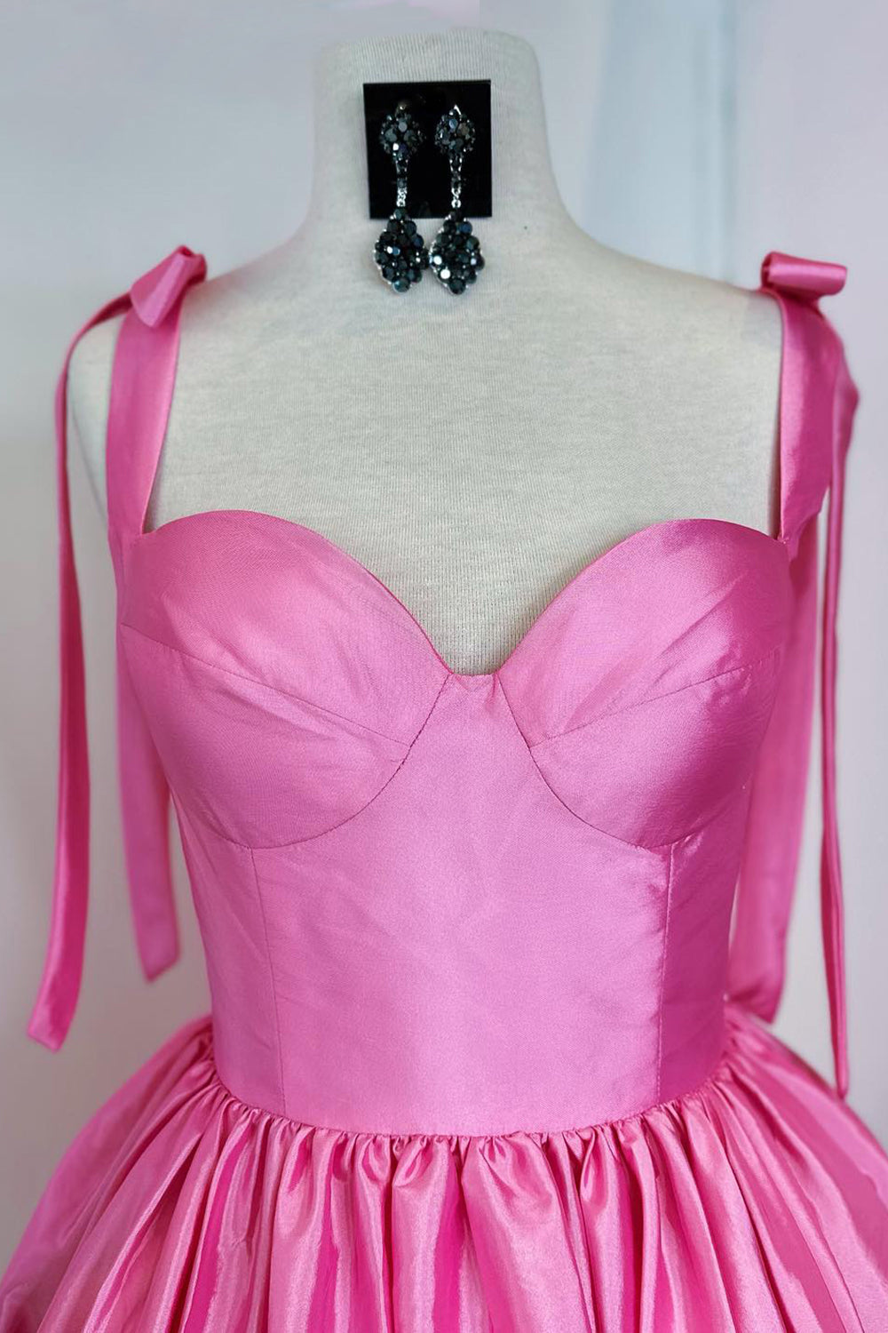 Robe de bal courte rose fuchsia à fines bretelles spaghetti et coupe princesse, ornée de fronces.