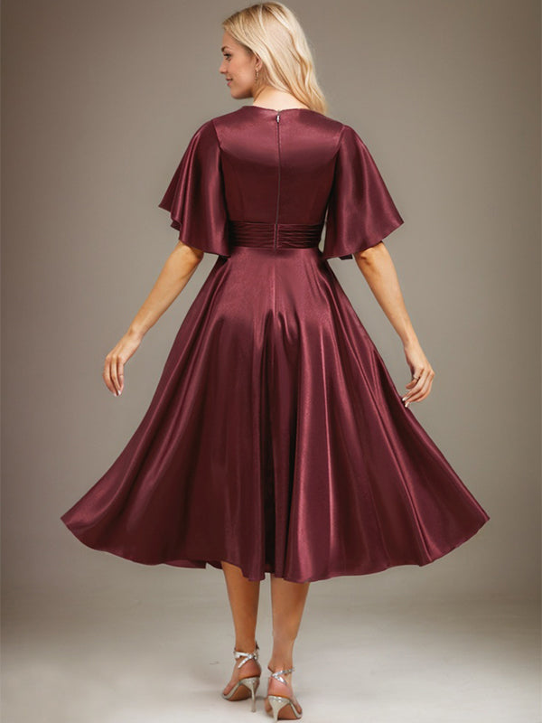 Vestido de novia de satén elástico, corte en A, escote en V, largo hasta la rodilla, con cuentas y pliegues. 
