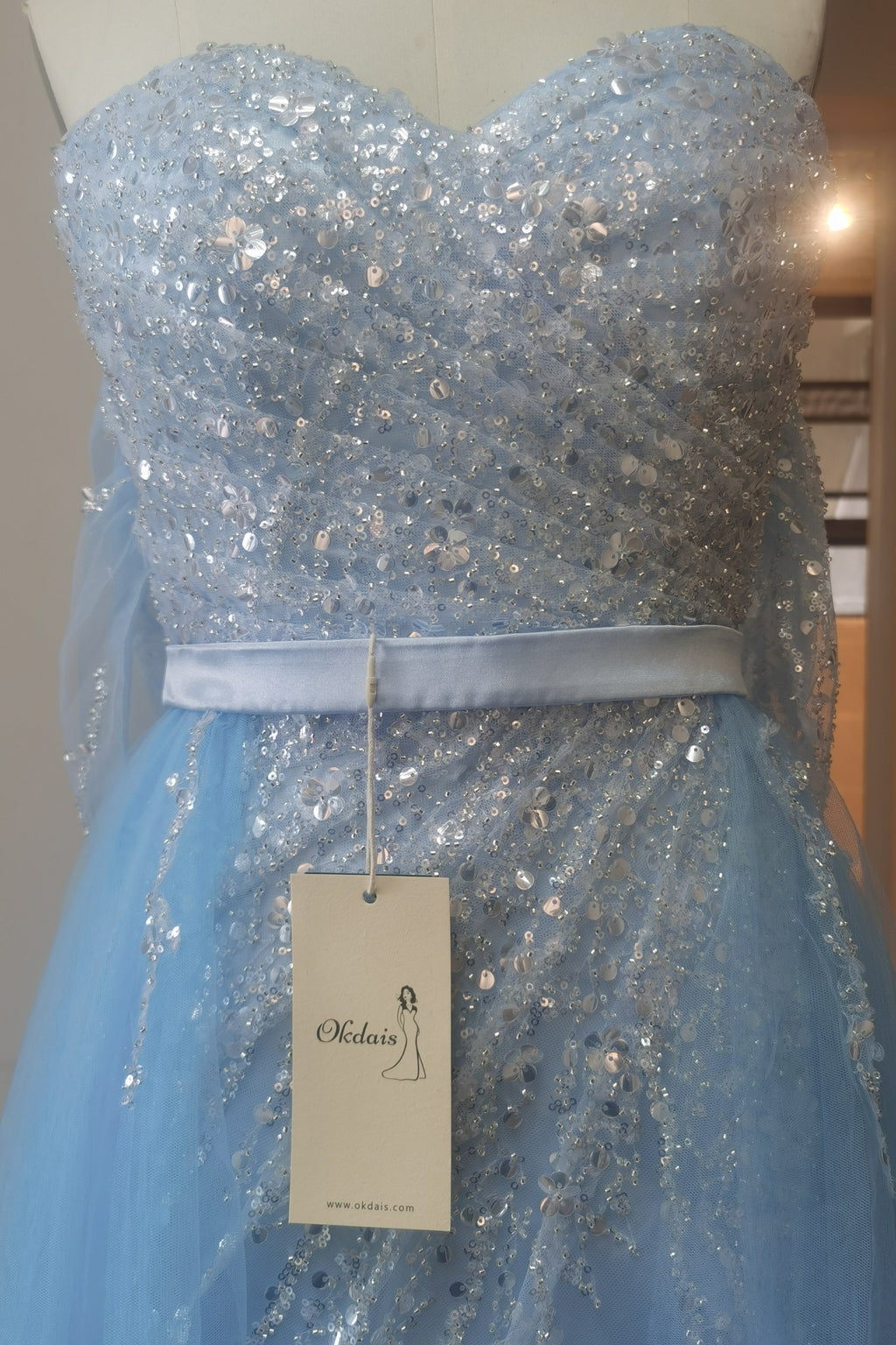 Robe de bal en tulle bleu ciel fendue sur le devant et épaules dénudées, ornée de sequins