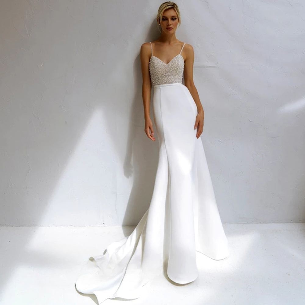 Vestido de novia de corte sirena con perlas, tirantes finos, satén, cuentas y escote en V. 