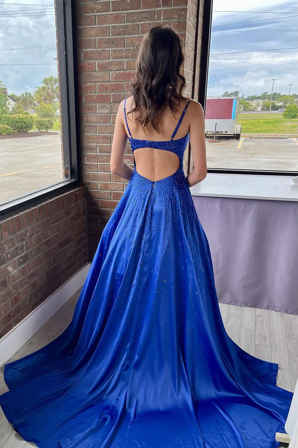 Vestido largo de fiesta azul real con tirantes finos, corte en A y detalles de pedrería.
