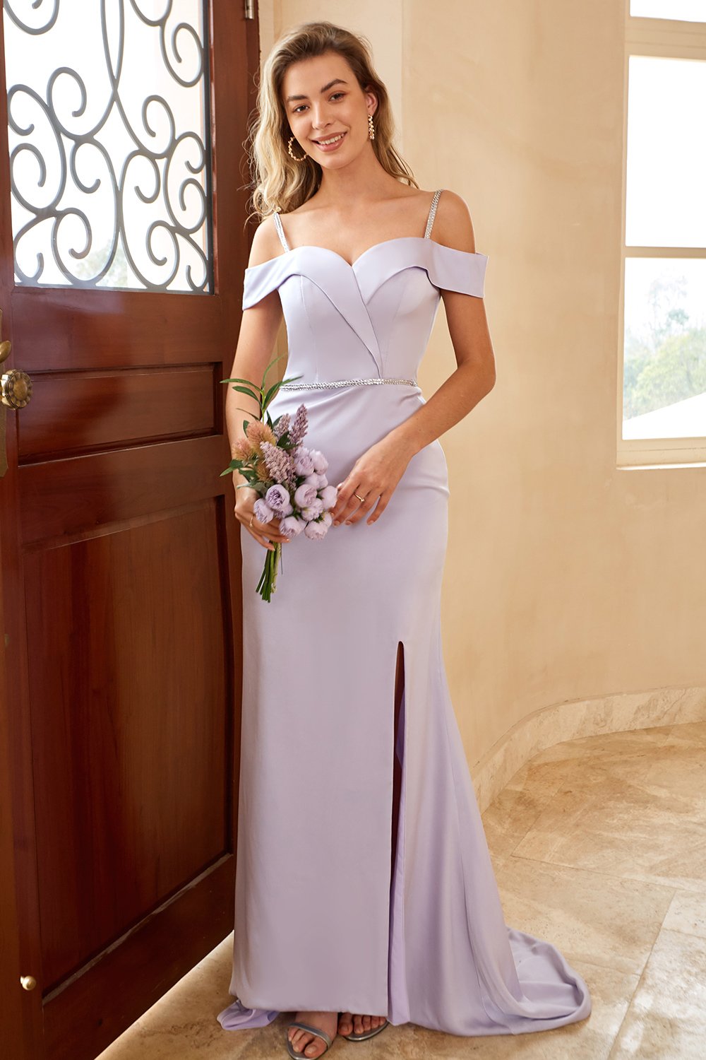 Vestido largo de dama de honor color lila, estilo tubo, con hombros descubiertos y abertura frontal.