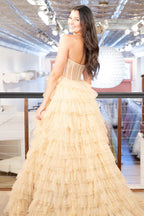 Robe de bal longue princesse en tulle doré, bustier et à volants, fendue.