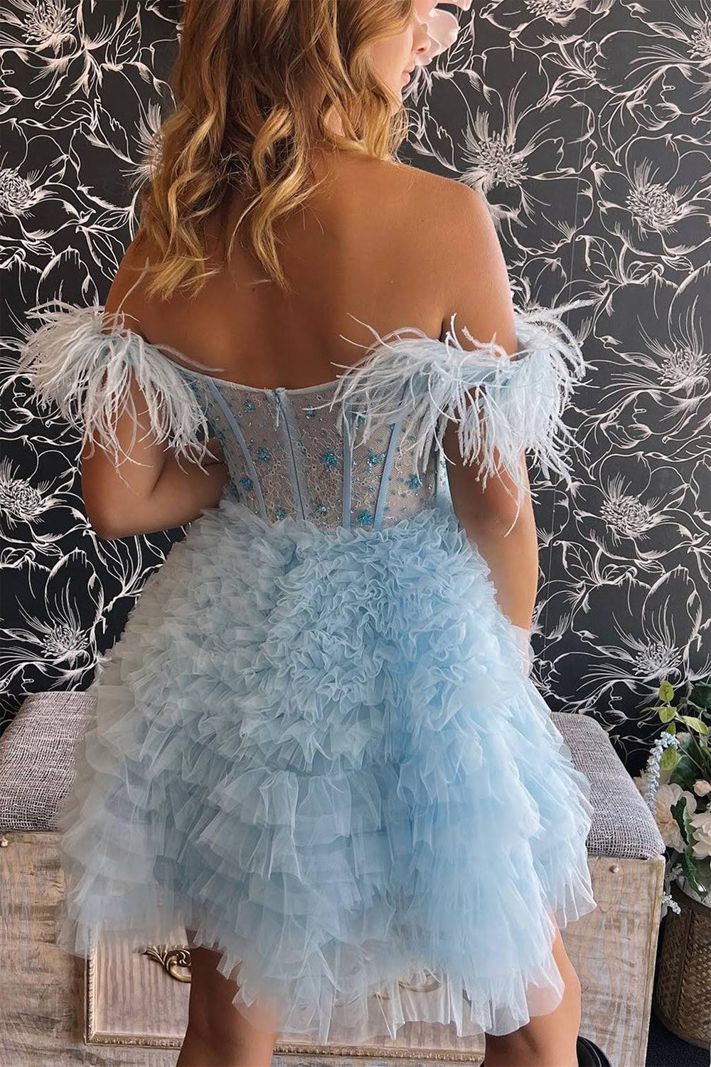 Un vestido corto rojo de fiesta con hombros descubiertos y plumas.