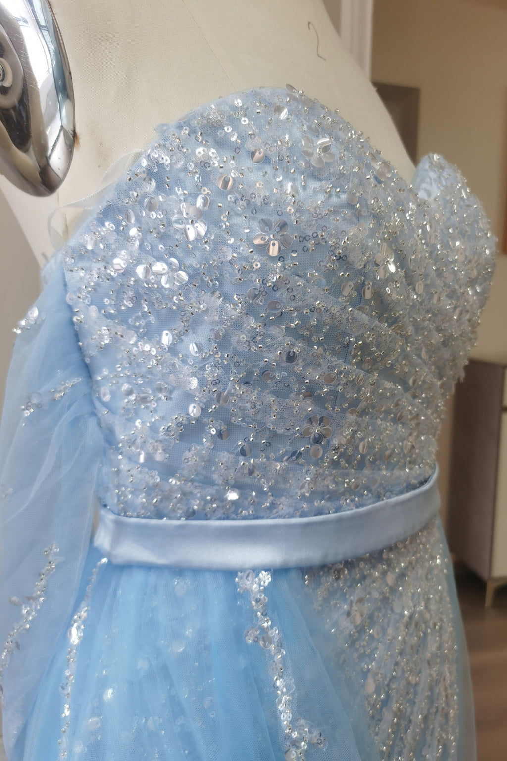 Robe de bal en tulle bleu ciel fendue sur le devant et épaules dénudées, ornée de sequins