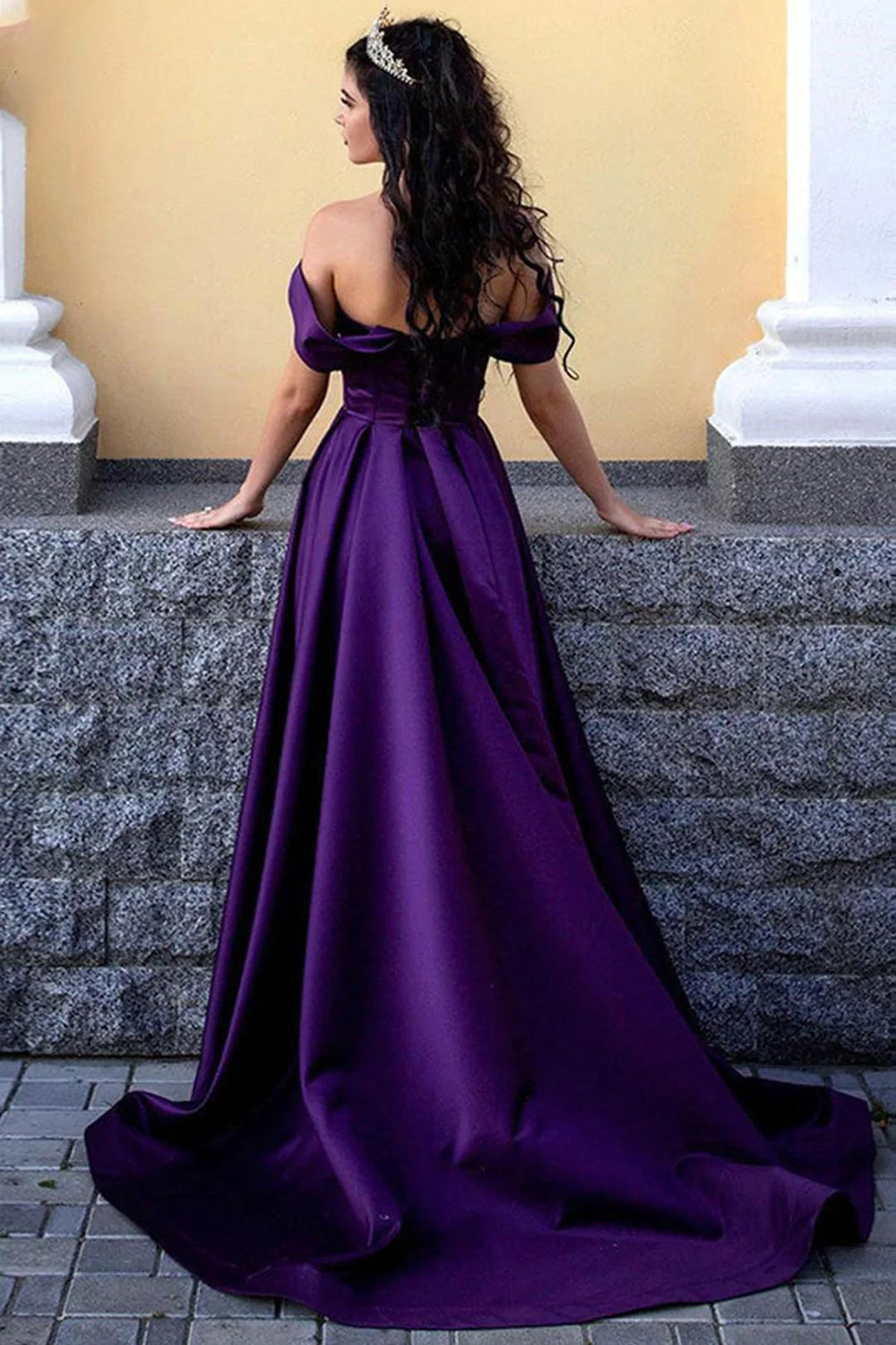 Vestido largo de fiesta morado con escote barco y abertura frontal.