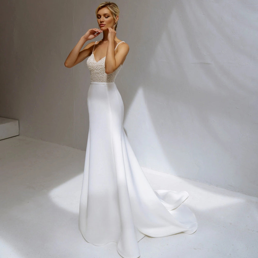 Vestido de novia de corte sirena con perlas, tirantes finos, satén, cuentas y escote en V. 