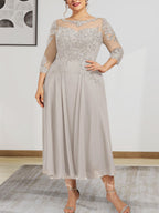 Robe de mariée trapèze en mousseline de soie et dentelle, longueur thé, ornée de perles et de sequins, avec décolleté en A et effet illusion.