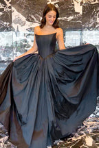 Vestido de fiesta negro de corte A, sin tirantes y con corsé, con espalda cruzada.
