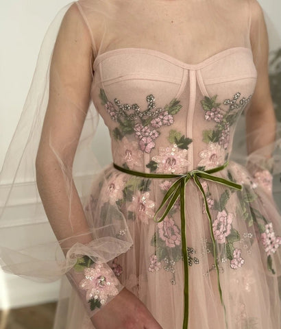 Robe de bal trapèze en tulle à manches longues et col rond, ornée de broderies florales.