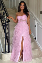 Vestido largo rosa de fiesta con corte en A, volantes, apliques y corsé, con abertura.