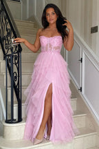 Vestido largo rosa de fiesta con corte en A, volantes, apliques y corsé, con abertura.