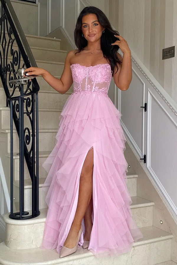 Vestido largo rosa de fiesta con corte en A, volantes, apliques y corsé, con abertura.