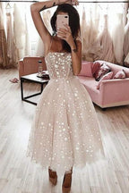 Vestido de fiesta rosa perla con tirantes finos, corte en A y largo hasta la rodilla, con cuentas.