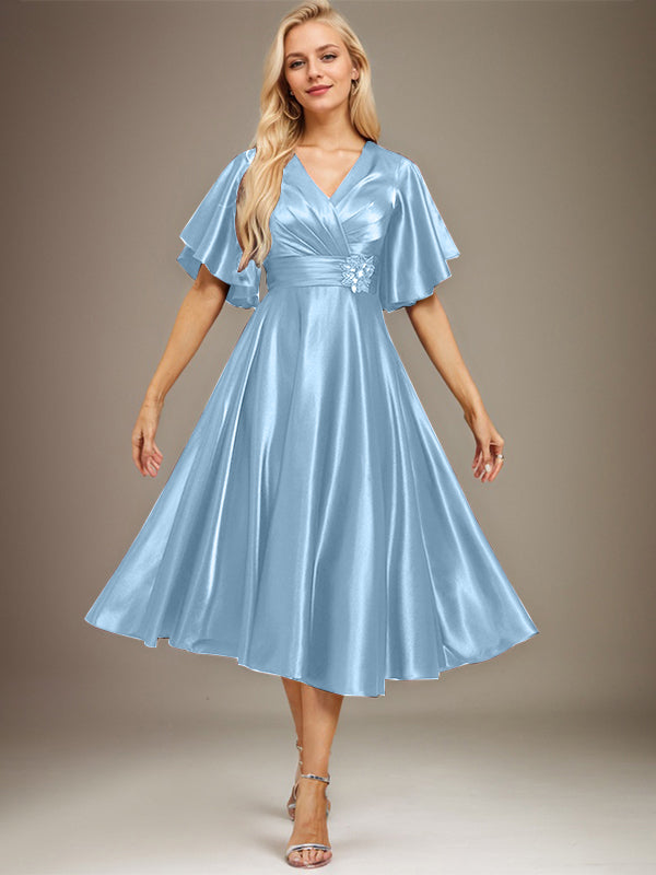Vestido de novia de satén elástico, corte en A, escote en V, largo hasta la rodilla, con cuentas y pliegues. 