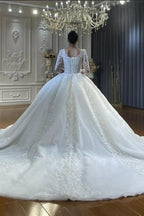Vestido de novia de corte princesa, escote corazón, tul, mangas largas, apliques y encaje hasta el suelo.
