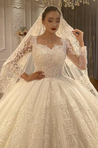 Vestido de novia de corte princesa, escote corazón, tul, mangas largas, apliques y encaje hasta el suelo.