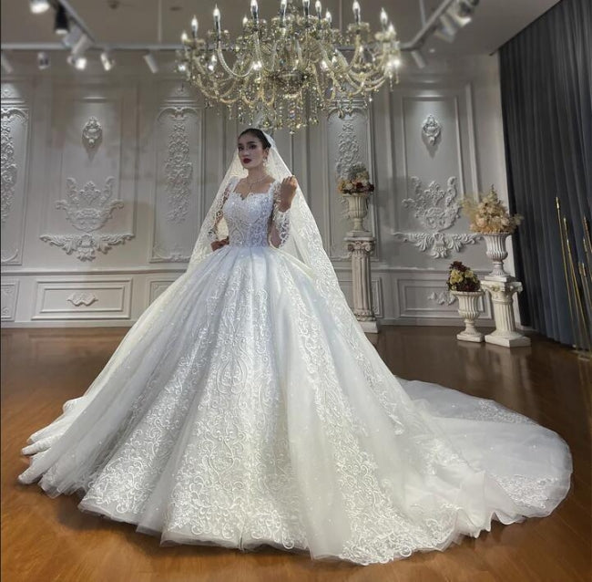 Vestido de novia de corte princesa, escote corazón, tul, mangas largas, apliques y encaje hasta el suelo.