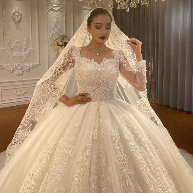 Vestido de novia de corte princesa, escote corazón, tul, mangas largas, apliques y encaje hasta el suelo.