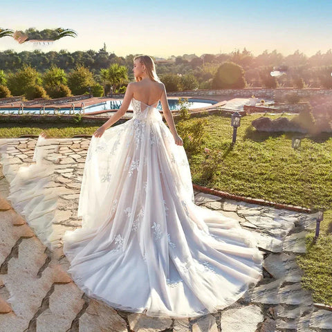 Vestidos de novia color marfil para mujer, estilo playa, colección verano 2023. Corte corazón, línea A, largo hasta el suelo, ilusión, espalda con lazo y apliques de encaje.