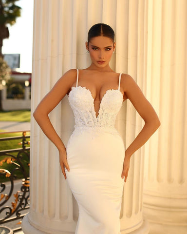 Magnifique robe de mariée sirène longue ivoire à fines bretelles spaghetti, en dentelle et satin lacé.