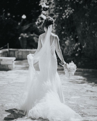 Magnifique robe de mariée sirène longue à fines bretelles, col en V, sans manches et dos nu en dentelle, ornée de fines bretelles et d'un décolleté en V.