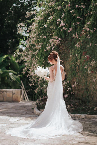 Magnifique robe de mariée sirène longue à fines bretelles, col en V, sans manches et dos nu en dentelle, ornée de fines bretelles et d'un décolleté en V.