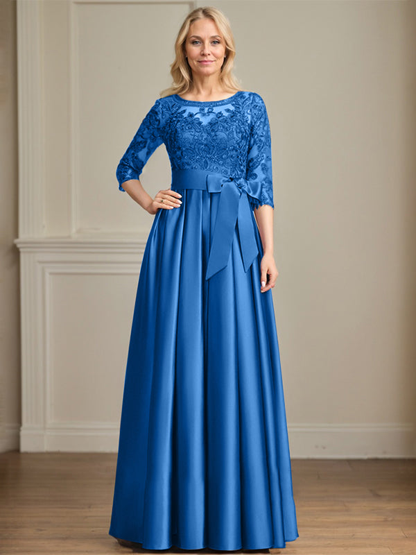 Robe de mariée longue en satin et dentelle, coupe trapèze, décolleté illusion, ornée d'un nœud à sequins. 