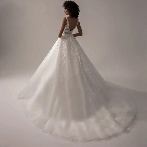 Robe de mariée bohème en dentelle appliquée, coupe trapèze, tulle vaporeux, sans manches, col en V, style formel, idéale pour une soirée à la plage ou une fête sur la plage.