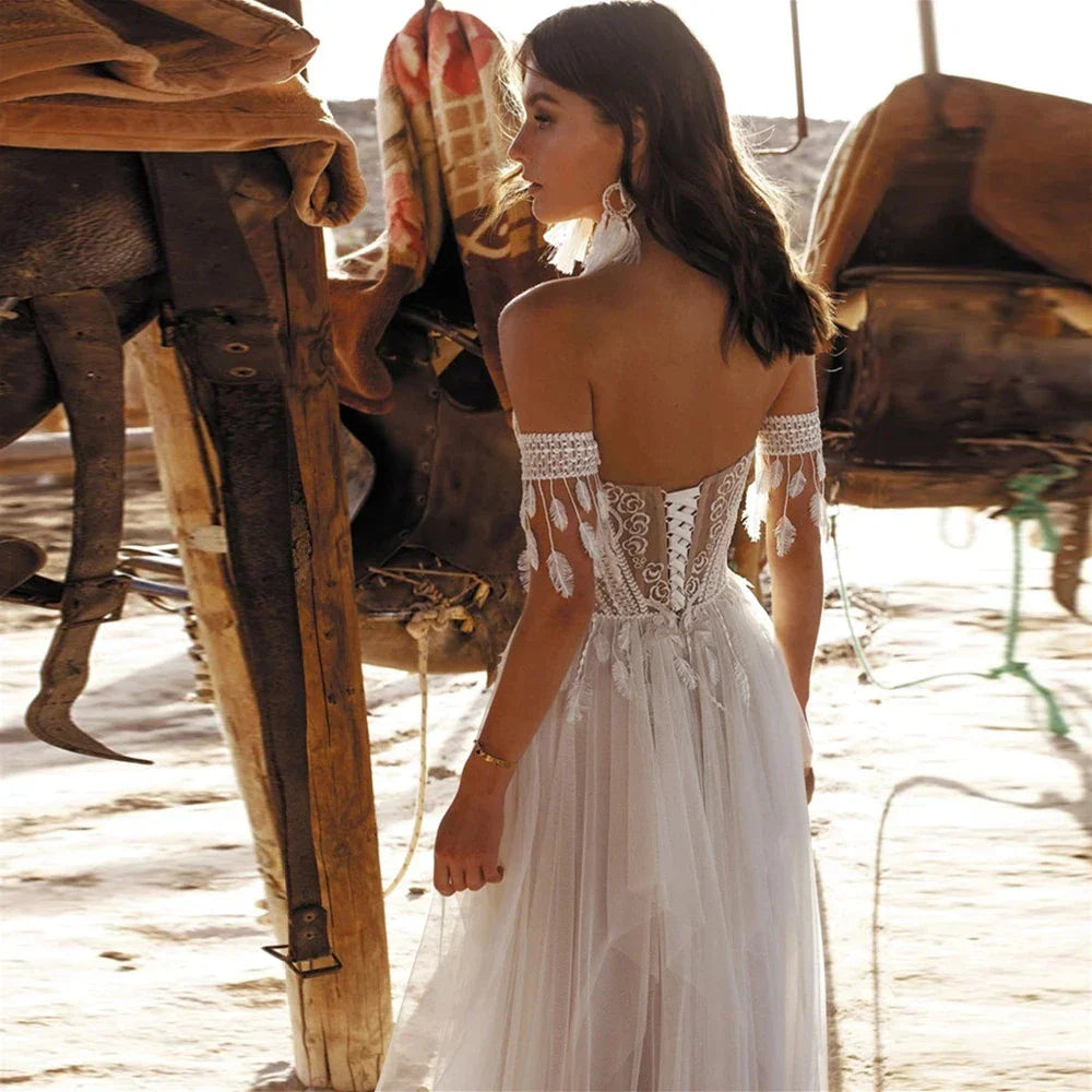 Robes de mariée bohèmes en dentelle, tulle et pompons, style plage, décolleté cœur, épaules dénudées, coupe trapèze, dos nu illusion, laçage, collection 2023